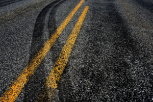 Tire marks crossing the yellow lines in the road. This image symbolizes and automobile accident in New York.